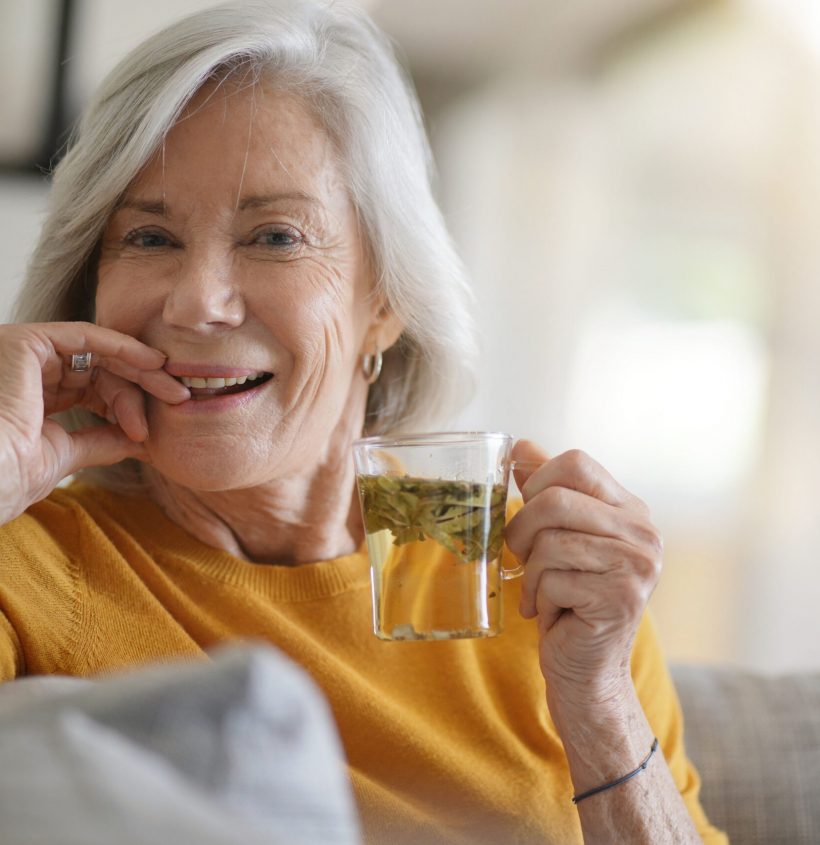 Beautiful senior woman at home with cup of loose leaf tea